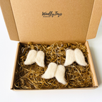 Három tűnemezelt fehér gyapjú angyalszárny függődísz elegáns kraft díszdobozban, arany és ezüst selyem zsinórokkal, készen az ajándékozásra.