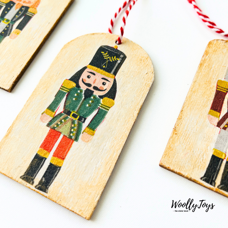 Közelkép egy szines kézműves diótörő mintás fa ajándékkísérőről, amelyen jól látszik a szalvéta technika minősége és a természetes fa erezete.