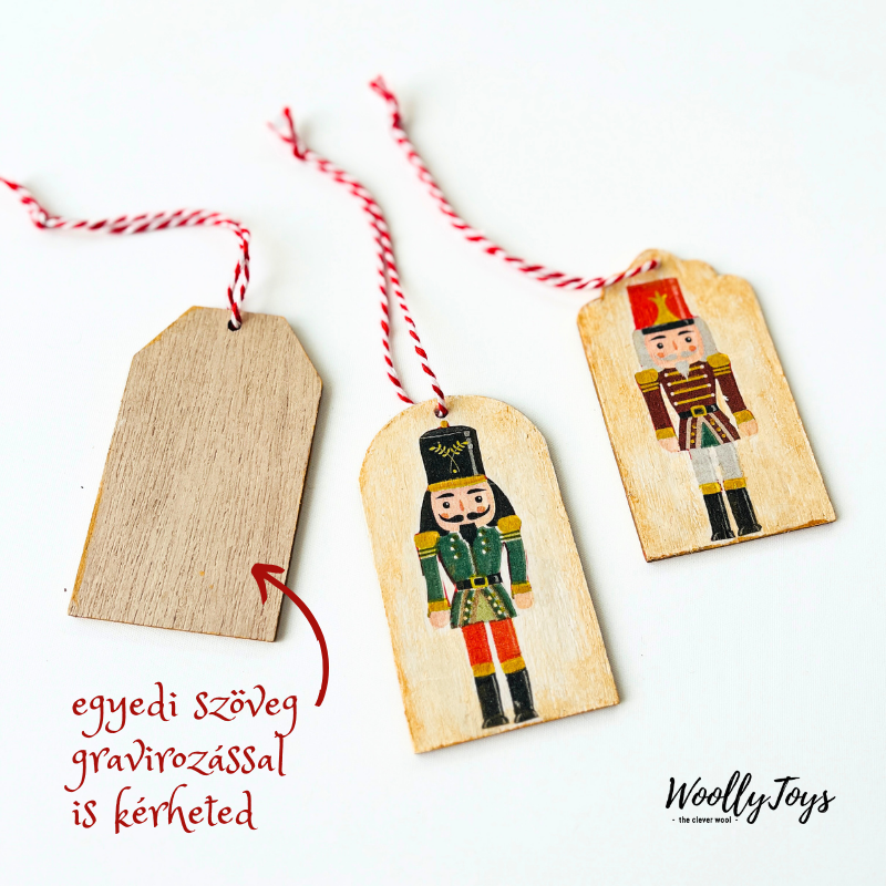 Három kézműves színes diótörő mintás fa ajándékkísérő egymás mellett bemutatva, a hátoldalukon jelölve a személyre szabható, gravírozható felületet.