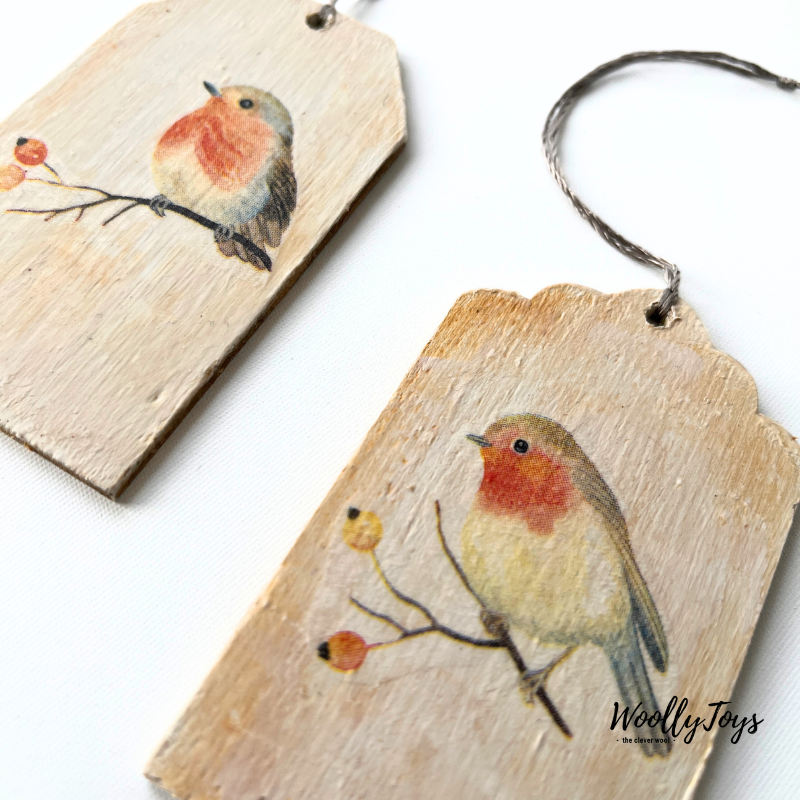 Közelkép egy kézműves szines vörösbegy mintás fa ajándékkísérőről, amelyen jól látszik a szalvéta technika minősége és a természetes fa erezete.