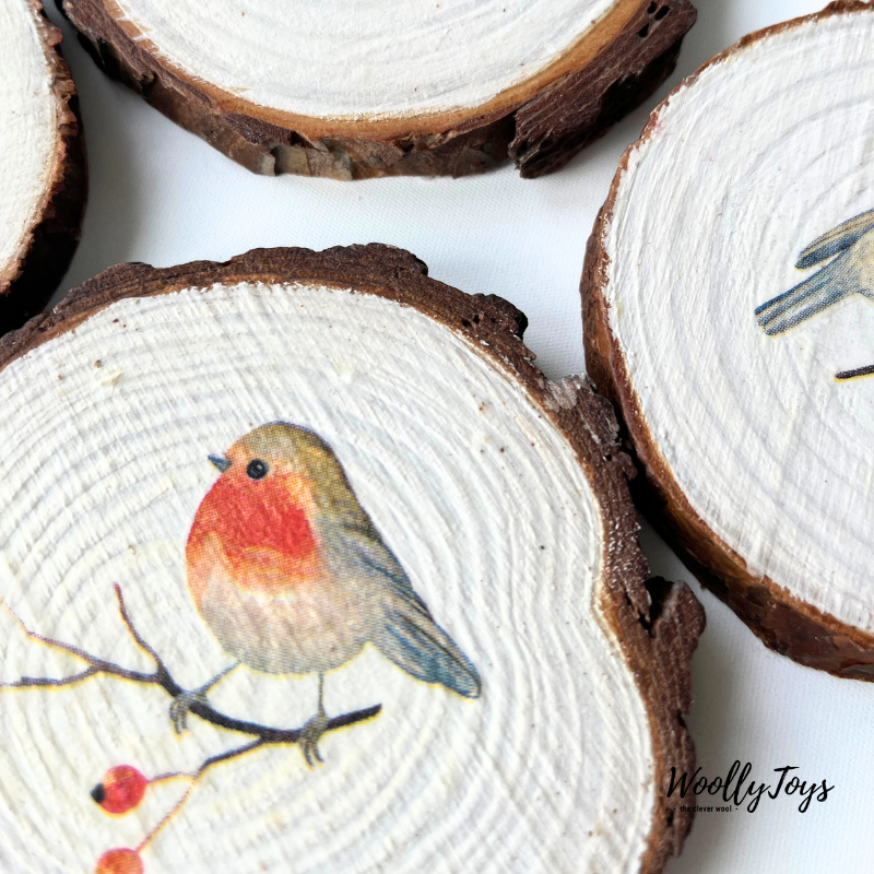 Közelkép egy szines, kézzel készült vörösbegy mintás fa poháralátétről, kiemelve a szalvéta technika finom részleteit és a rusztikus fa struktúrát.