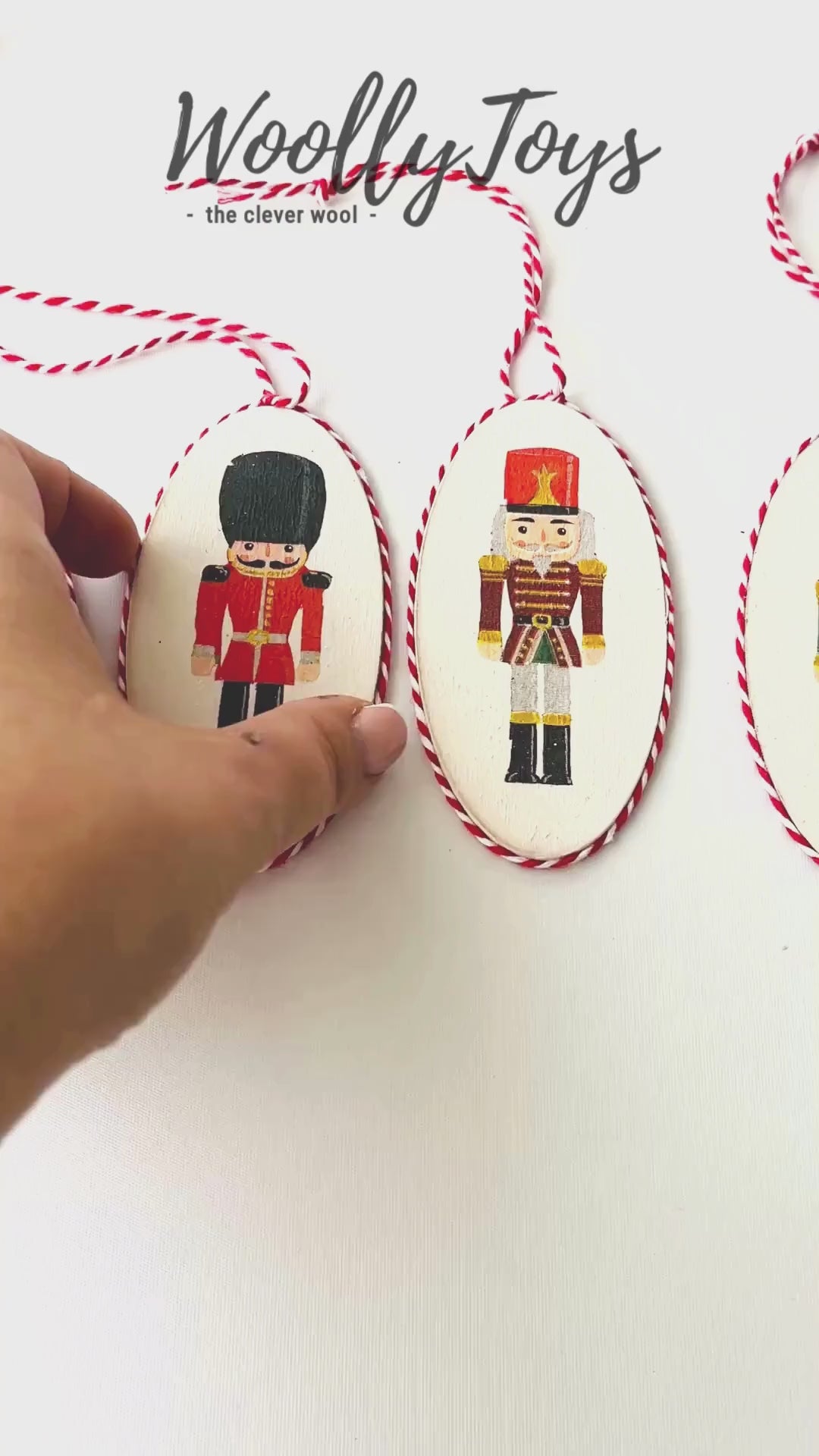 Videó, amelyen egy kéz mutatja be a kézműves diótörő mintás fa karácsonyfadíszt körbeforgatva, kiemelve a szalvéta technika részleteit és a fa textúráját.