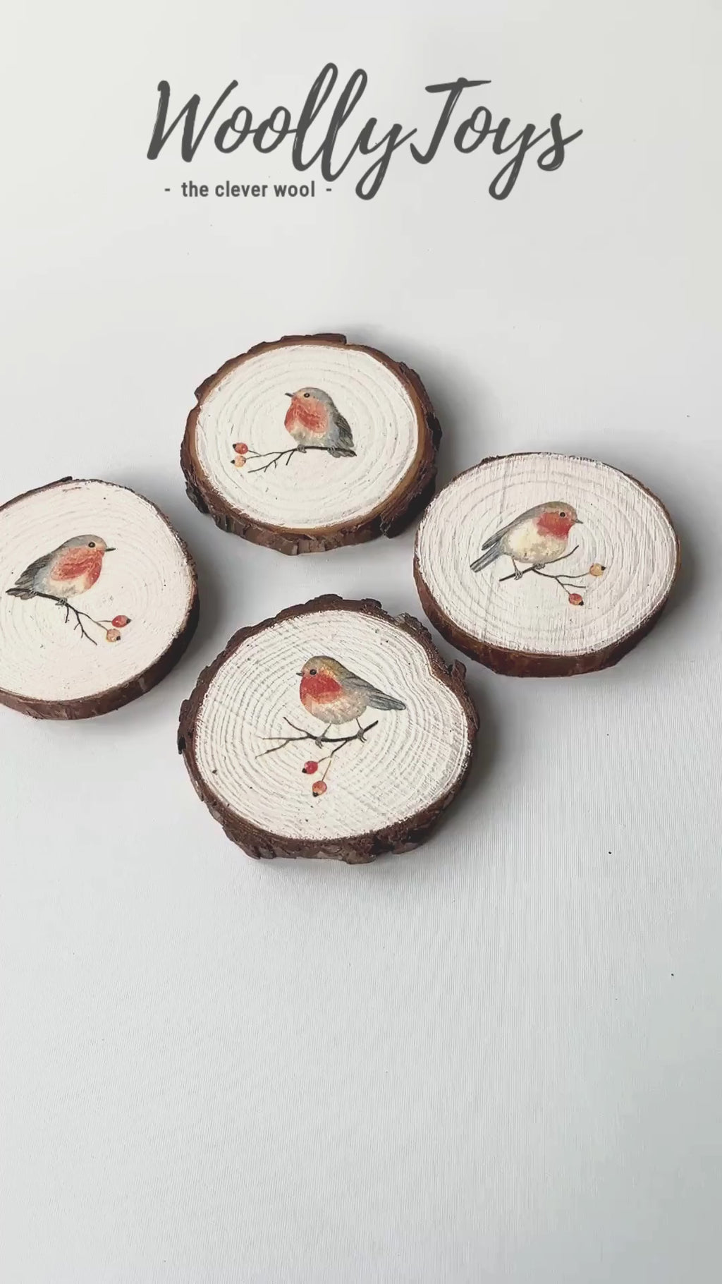 Videó, amelyen egy kéz mutatja be a kézműves szines vörösbegy mintás fa poháralátétet minden oldalról, kiemelve a szalvéta technikát és a gravírozható fa hátoldalt.